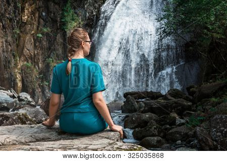 Woman at Korbu Waterfall on the Lake Teletskoye in autumn Altai Mountains.