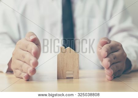 Insurance Home Protection Concept. Man Hands Prevent Wooden House