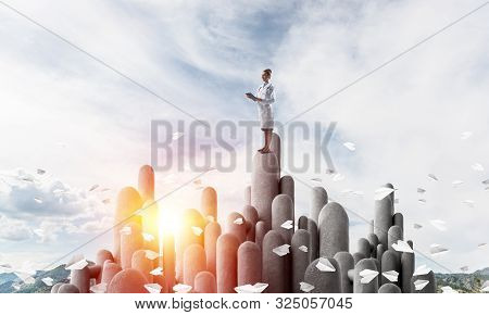 Young Female Doctor With Folder In Hands Satnding On Stone Column