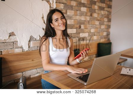 Attractive Smart Girl Working On Laptop In Cafe. Beautiful Girl Using Computer For Work. Girl Grinki