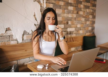 Attractive Smart Girl Working On Laptop In Cafe. Beautiful Girl Using Computer For Work. Girl Grinki