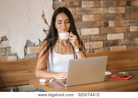Attractive Smart Girl Working On Laptop In Cafe. Beautiful Girl Using Computer For Work. Girl Grinki