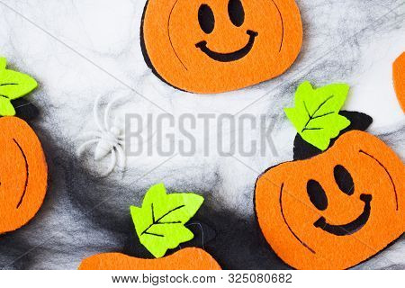 Top View Of Halloween Crafts, Felt Handmade Pumpkins, Black Patina On White Paper Background With Co