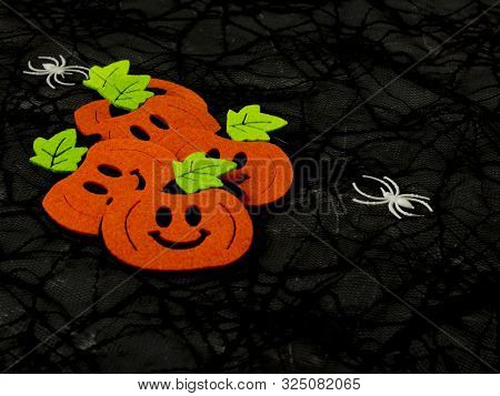 Top View Of Halloween Crafts, Orange Felt Pumpkins On A Black Web Background With Copy Space For Tex