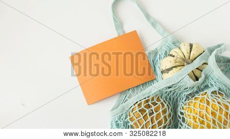Autumn Flat Lay Composition With Orange Pumpkins In Mesh Shopping Bag On White Background. Creative 