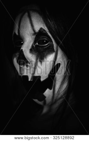 Spooky Pumpkin Face Of A Halloween Creature With Opened Mouth On Black Background. Close-up Monochro