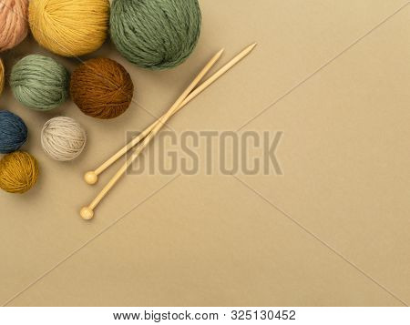 Various Size And Color Balls Of Yarn Arranged As Left Top Corner Frame With Wooden Knitting Needles.