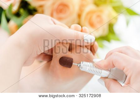 Podiatrist in podiatry session working of feet of client with machine