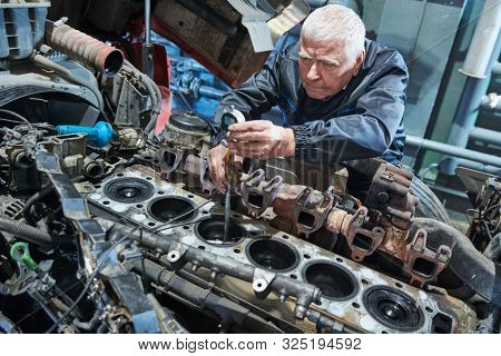 Truck repair service. Serviceman measuring cylinder