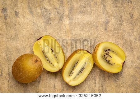 row of cut gold kiwifruit berries against  textured bark paper with a copy space