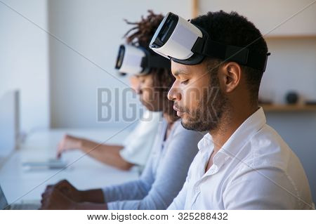 Team Of Vr Developers Working On Project. Man And Women Wearing Vr Headset, Sitting At Long Desk, Us