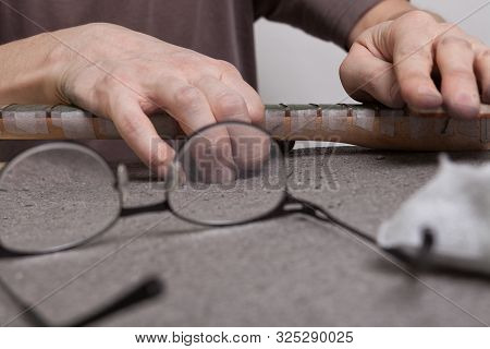 The Master Polishes The Frets Of The Guitar Fretboard With Paste.