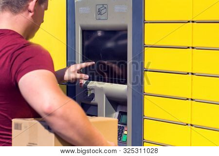 Man Client Using Automated Self-service Post Terminal Machine Or Locker To Depisit A Parcel For Stor