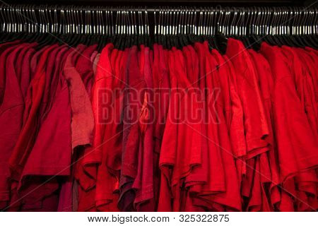 Red T-shirts on hangers on a shop wardrobe closet rail