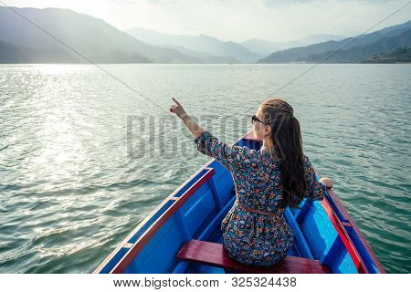 Beautiful And Young Woman In A Boat On A Lake In The Background Of Mountains. The Concept Of Outdoor