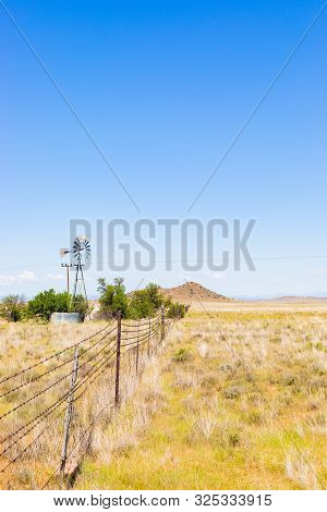 Windmill On A Farm In Rural Grassland Area Of South Africa