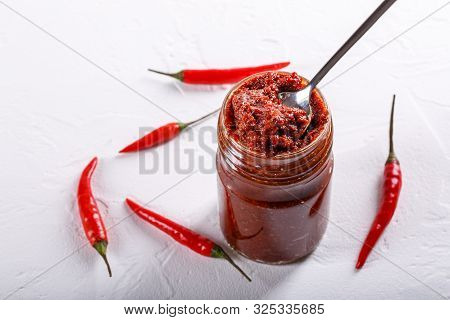 Hot Chili Pepper Paste. Red Sauce In Glass Jar On White Background. Adjika Or Ajika In Georgian Cuis