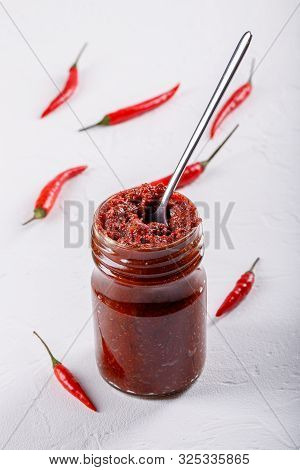 Hot Chili Pepper Paste. Red Sauce In Glass Jar On White Background. Adjika Or Ajika In Georgian Cuis