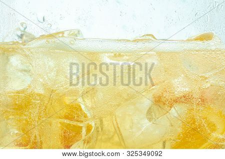 Close Up Of Lemon Slices In Stirring The Lemonade And Ice Cubes On Background. Texture Of Cooling Sw