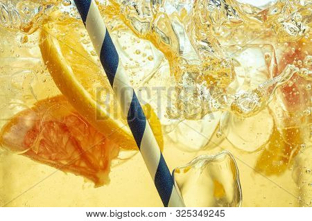 Close Up Of Lemon Slices In Stirring The Lemonade And Ice Cubes On Background. Texture Of Cooling Sw