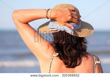 Woman With Straw Hat Waiting By The Ocean