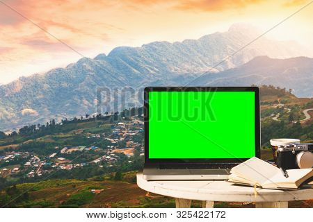 Mockup Image Of Laptop With Empty Screen With Camera,notebook,coffee Cup On Table With At Mountanis 