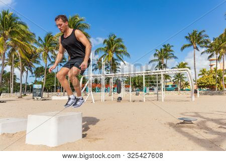 Jump box training man atlhete jumping doing strength workout outside in beach calisthenics park in South Beach, Miami, Florida.