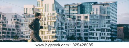 City lifestyle winter run runner athlete man jogging outside on modern apartment building background panoramic banner. Running active living people panorama.