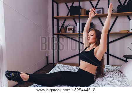 Attrctive Fitness Woman Doing Stretching Exercises At Home, As Part Of A Healthy Lifestyle Without G