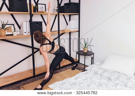 Attrctive Fitness Woman Doing Stretching Exercises At Home, As Part Of A Healthy Lifestyle Without G