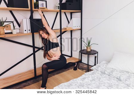 Attrctive Fitness Woman Doing Stretching Exercises At Home, As Part Of A Healthy Lifestyle Without G
