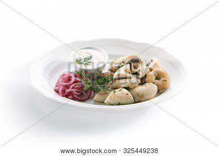 Pickles set with homemade pickled milk mushrooms, marinated red onion rings and sour cream on white restaurant plate isolated. Salted Lactarius resimus mushroom with oil and fresh chopped dill