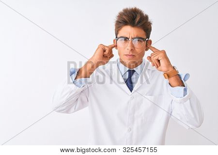 Young handsome sciencist man wearing glasses and coat over isolated white background covering ears with fingers with annoyed expression for the noise of loud music. Deaf concept.
