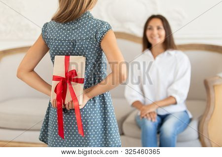 Litle Girl Hides Gift Box For Her Mother Behind Own Back. Selective Focus