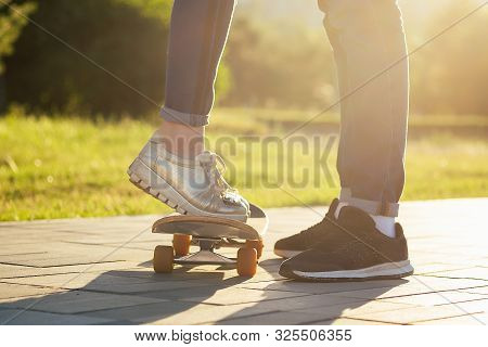 Couple In Love In A Summer Park. Legs Feet Of A Man And A Woman In Fashionable Jeans And Stylish Sne