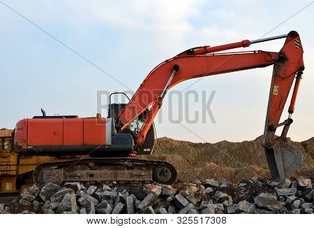 Heavy Excavator Working At Gravel Quarry Unloads Old Concrete Stones For Crushing And Recycling To G
