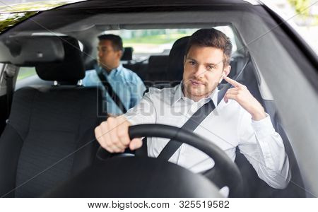 transport, vehicle and people concept - male driver with wireless earphones or hands free device driving car with passenger