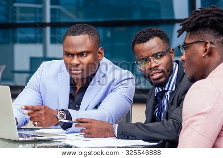 A Group Of Three Stylish African American Men Entrepreneurs In Fashion Business Suits Working Sittin