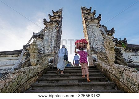 Unidentified Man And Woman With Offering At Temple Gate In Pura Penataran Agung Lempuyang Bali, Indo