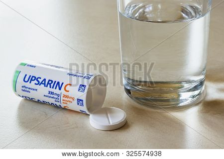 Varna, Bulgaria, October 02, 2019. Upsarin C Antipyretic Tablets And Glass Of Water On A White Table