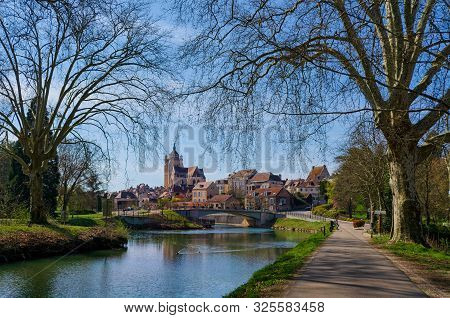 View Of The Old French City Of Dole From The Side Of The Park. In The Foreground Is A Water Channel 