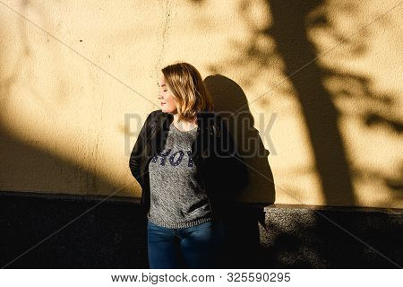 Happy Young Curvy Woman Standing Near Yellow Wall. Girl Enjoying Warm Sunny Weather. She Wearing In 