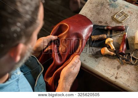 Craftsman touching leather, close-up. A raw material, stuffs and preparation of leather craft work.
