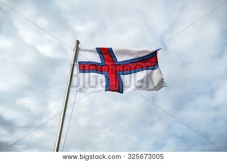 Flag of Faroe islands waving against a cloudy sky