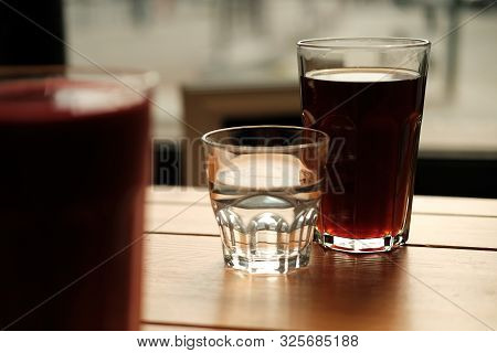 Alternative Coffee And A Glass Of Water Stand On A Wooden Table. Dark Background. Close-up