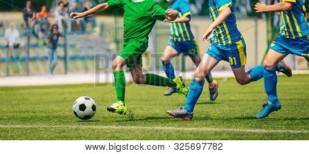 Junior Level Football Competition. School Soccer Tournamrnt. Group Of Boy Running After Ball On Rumm