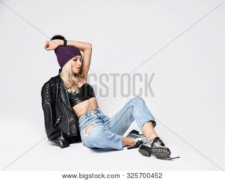 Tired Punk Style Blonde Woman In Torn Jeans, Leather Bralet, Leather Jacket With Zippers, Untied Chr