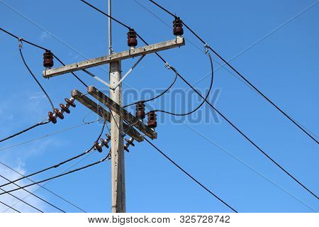 Power Line Post With Electrical Wires And Capacitors Isolated On Blue Sky Background. Electricity Tr