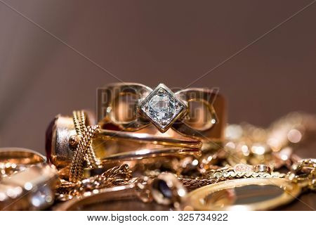 Real Gold Rings With Diamonds, Gems, Neckless On Dark Cracked Wood Background Close Up Macro Shot.