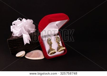 Decorated Brown Lether Box And Beautiful Gold Plated Earrings In Red Gift Box With Seashells On Blac